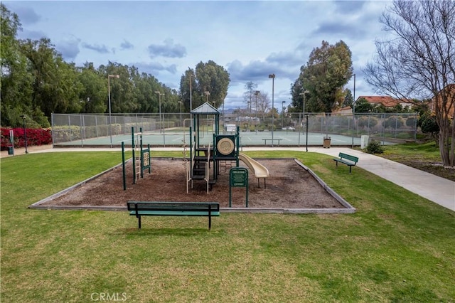 communal playground featuring a yard and fence