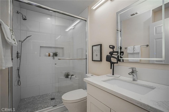 bathroom featuring toilet, a shower stall, visible vents, and vanity