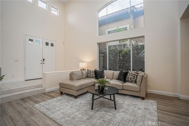 living room with a high ceiling, baseboards, and wood finished floors