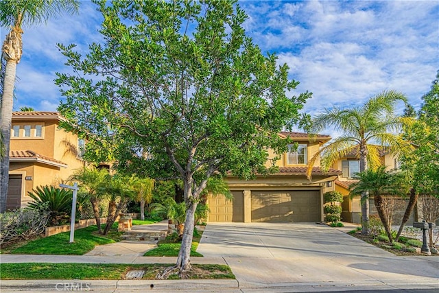 mediterranean / spanish house with a tile roof, driveway, an attached garage, and stucco siding