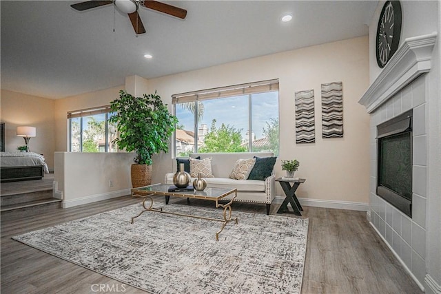 living area with recessed lighting, baseboards, wood finished floors, and a tile fireplace