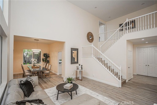 living room with stairway, wood finished floors, a towering ceiling, and baseboards