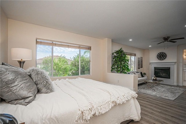 bedroom featuring multiple windows, a tiled fireplace, wood finished floors, and recessed lighting