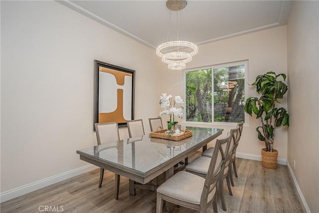 dining room with a chandelier, crown molding, light wood-style flooring, and baseboards