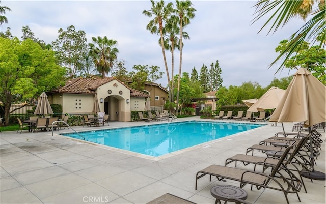 community pool with a patio area and fence