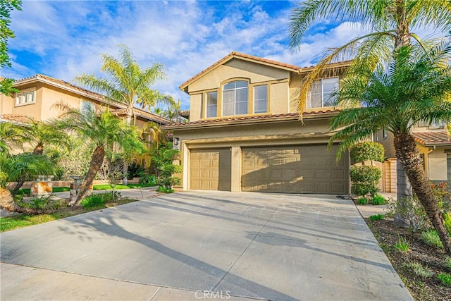 mediterranean / spanish-style home featuring driveway, an attached garage, a tile roof, and stucco siding