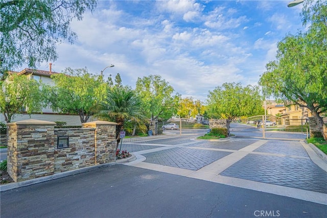 view of road featuring a gate, a gated entry, and curbs