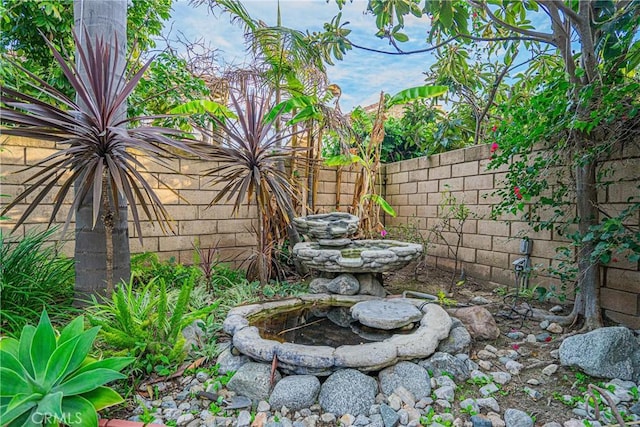 view of yard featuring fence and a garden pond