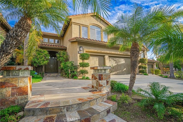 mediterranean / spanish-style home with concrete driveway, an attached garage, a tile roof, and stucco siding