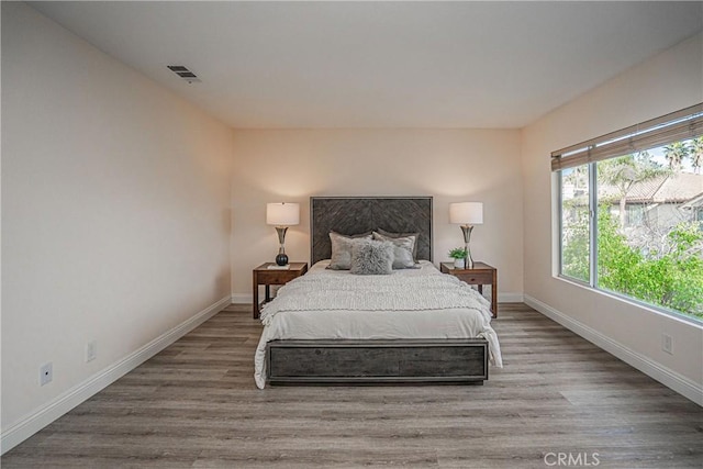 bedroom featuring wood finished floors, visible vents, and baseboards