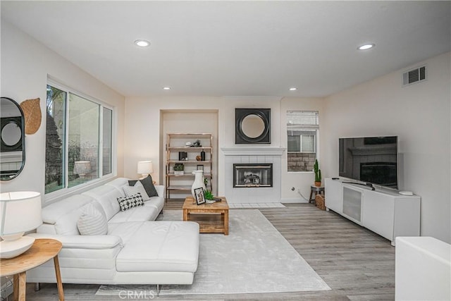 living area featuring a fireplace, visible vents, wood finished floors, and recessed lighting