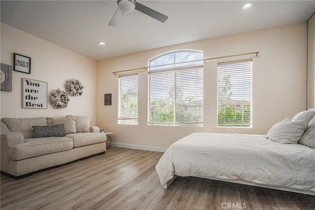 bedroom with recessed lighting, multiple windows, baseboards, and wood finished floors