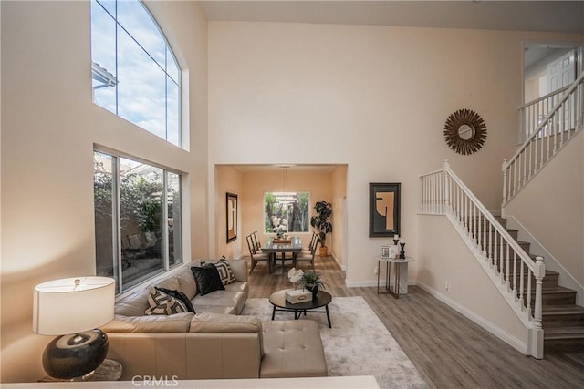 living room with wood finished floors, a high ceiling, baseboards, and stairs