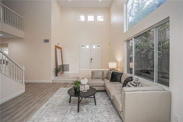 living area with stairs, wood finished floors, visible vents, and a healthy amount of sunlight