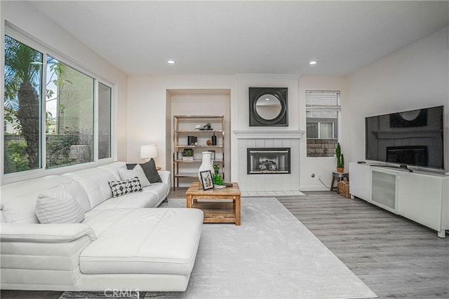 living area featuring a tile fireplace, recessed lighting, and wood finished floors