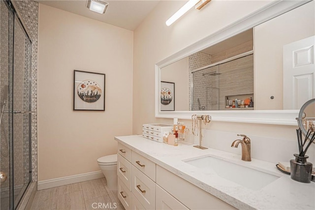 full bathroom featuring toilet, a stall shower, baseboards, and vanity