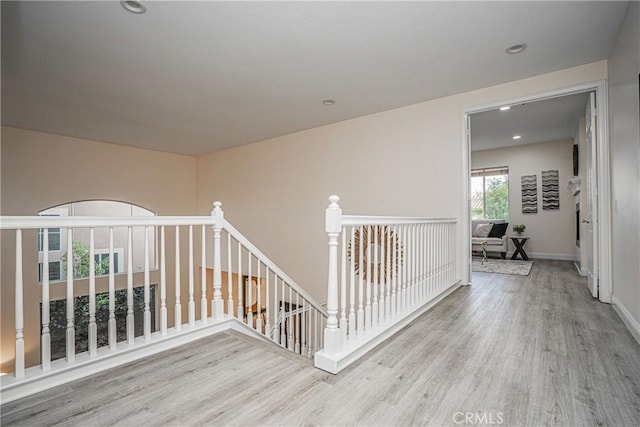 corridor with recessed lighting, baseboards, wood finished floors, and an upstairs landing