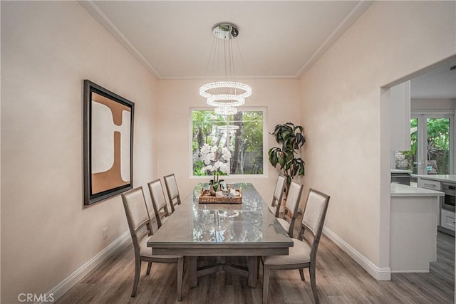 dining room featuring baseboards, crown molding, a chandelier, and wood finished floors