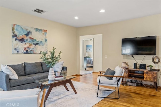 living room featuring baseboards, visible vents, wood finished floors, and recessed lighting