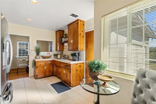 kitchen featuring a sink, visible vents, light countertops, freestanding refrigerator, and tasteful backsplash