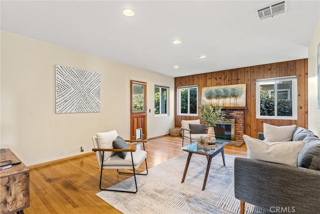 living room featuring light wood-type flooring, baseboards, visible vents, and a glass covered fireplace