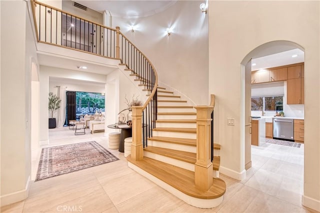 staircase with baseboards, visible vents, and a high ceiling