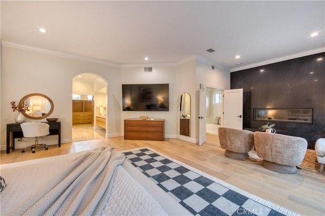 bedroom with visible vents, light wood-style flooring, recessed lighting, and arched walkways