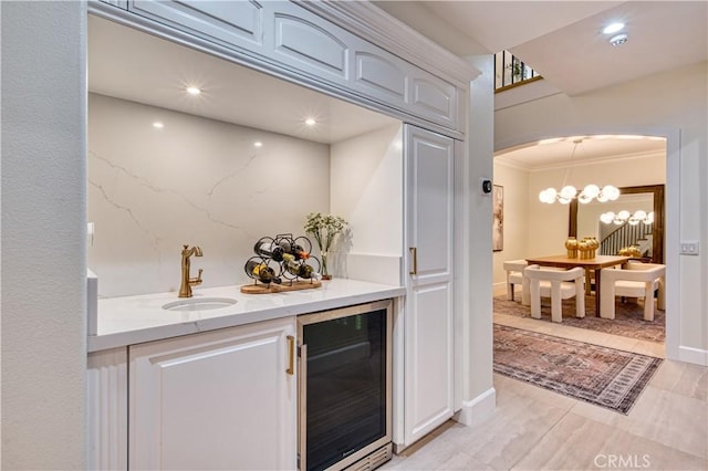 bar featuring arched walkways, a sink, bar area, wine cooler, and crown molding
