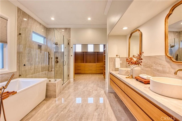 bathroom featuring a garden tub, double vanity, ornamental molding, a sink, and a shower stall