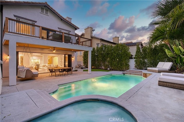 pool at dusk featuring an in ground hot tub, an outdoor living space, a patio, and a fenced in pool