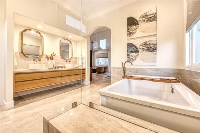 ensuite bathroom featuring ornamental molding, a garden tub, vanity, and connected bathroom