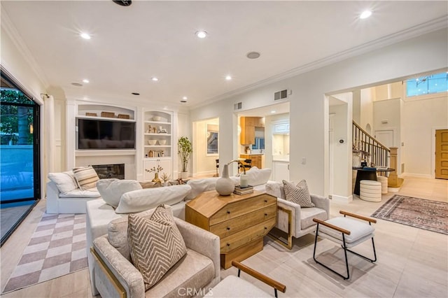 living area with ornamental molding, built in shelves, a glass covered fireplace, and recessed lighting