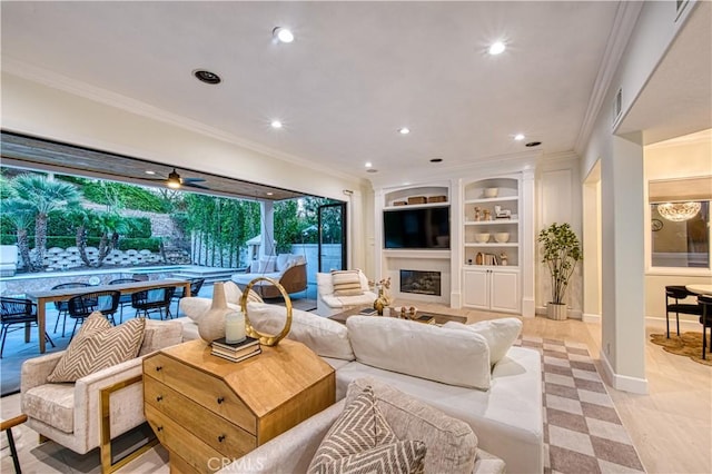 living room featuring recessed lighting, built in shelves, ornamental molding, and a glass covered fireplace