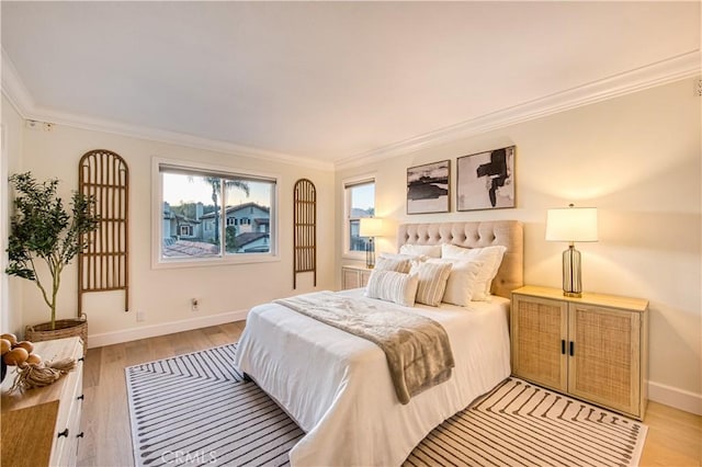 bedroom with crown molding, light wood finished floors, and baseboards