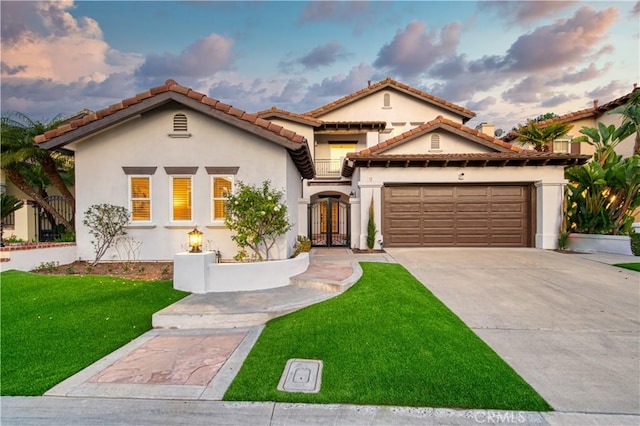 mediterranean / spanish home with french doors, stucco siding, concrete driveway, an attached garage, and a front lawn