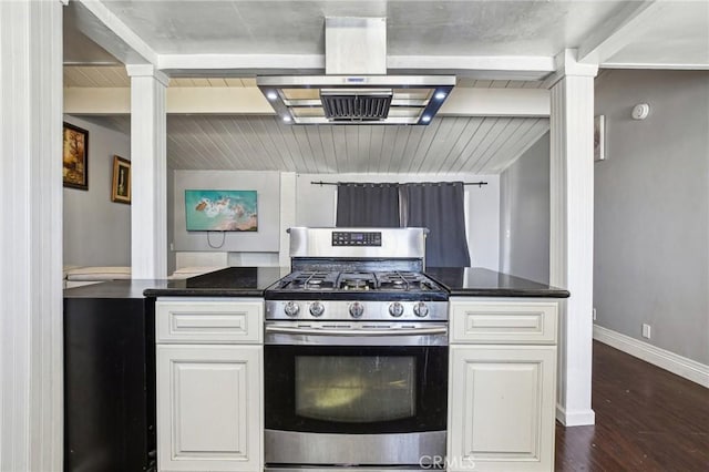 kitchen with dark countertops, white cabinetry, stainless steel gas range oven, and island range hood