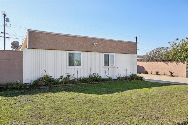 view of property exterior with fence and a lawn