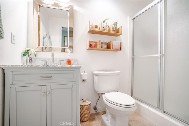 bathroom featuring a shower stall, toilet, and vanity