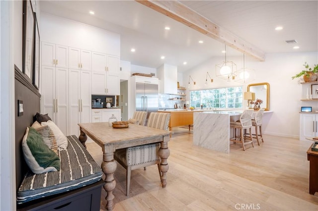 kitchen with lofted ceiling with beams, a kitchen island, white cabinets, and pendant lighting