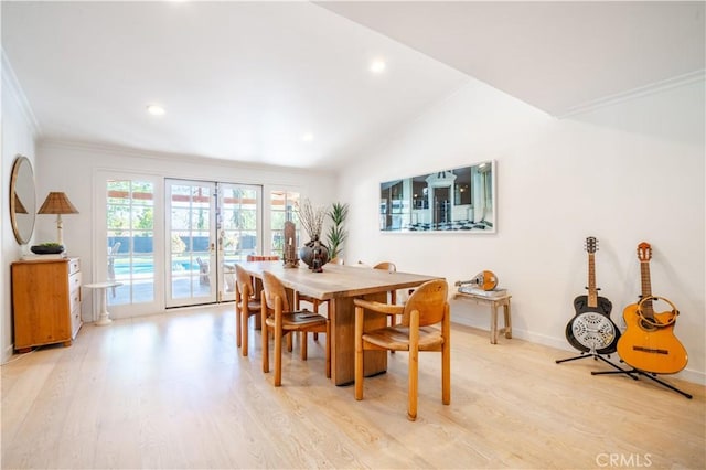 dining area with light wood finished floors, baseboards, vaulted ceiling, and crown molding