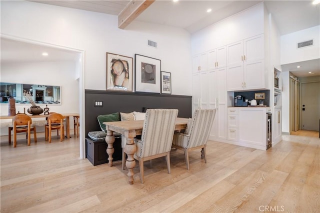 dining space with high vaulted ceiling, light wood finished floors, visible vents, and beamed ceiling