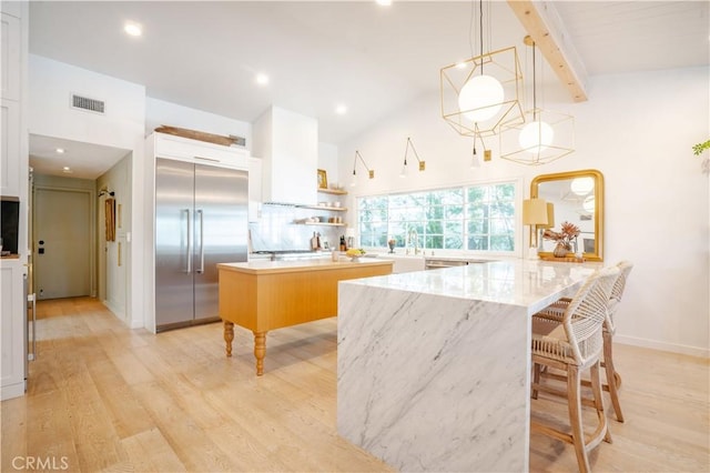 kitchen featuring built in fridge, decorative light fixtures, open shelves, white cabinets, and a kitchen island