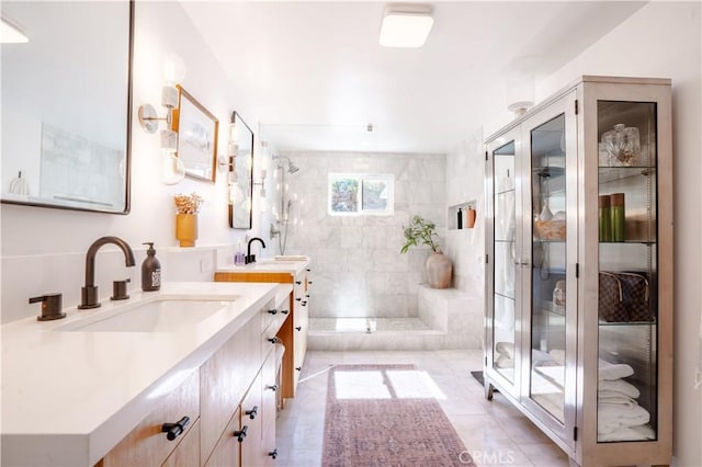 full bathroom featuring a stall shower, tile patterned flooring, two vanities, and a sink