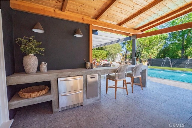 view of patio featuring a bar, fence, and a fenced in pool