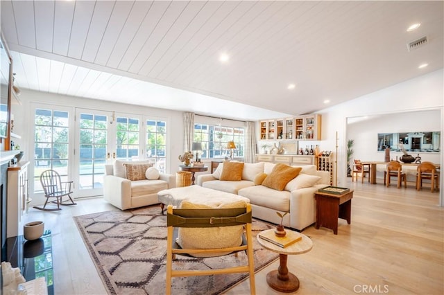 living room with lofted ceiling, recessed lighting, visible vents, light wood-style floors, and a glass covered fireplace