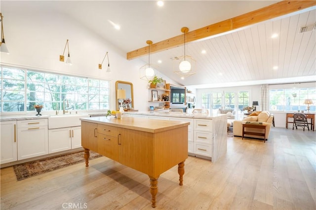 kitchen featuring a kitchen island, white cabinetry, open floor plan, light countertops, and hanging light fixtures