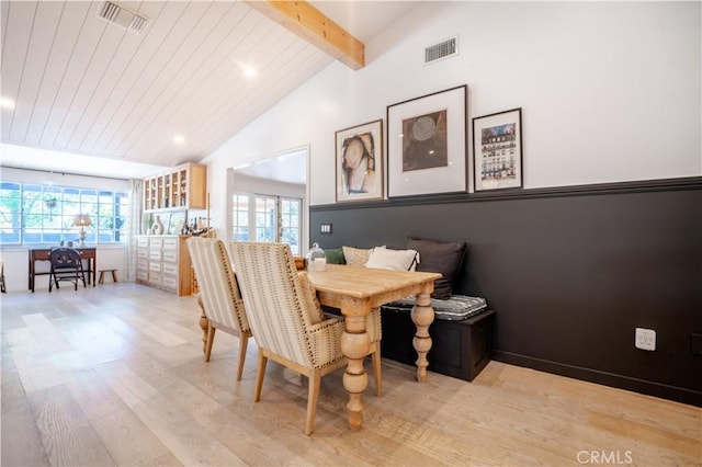 dining area with lofted ceiling with beams, light wood-type flooring, visible vents, and breakfast area