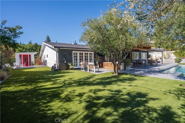 rear view of property with a lawn, an outdoor pool, a patio, and french doors