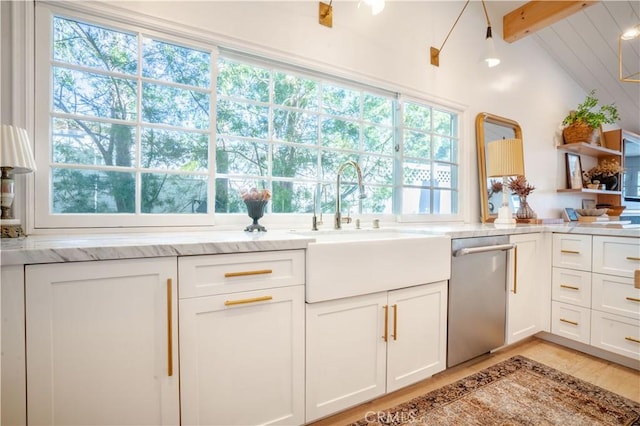 kitchen with a wealth of natural light, stainless steel dishwasher, a sink, and white cabinetry