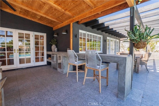 view of patio featuring french doors, outdoor dry bar, and a pergola